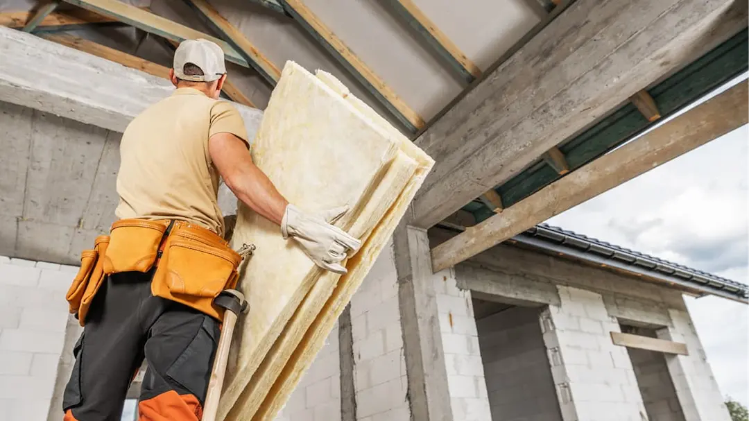 Un ouvrier certifié posant des plaques de laine de verre dans une maison.